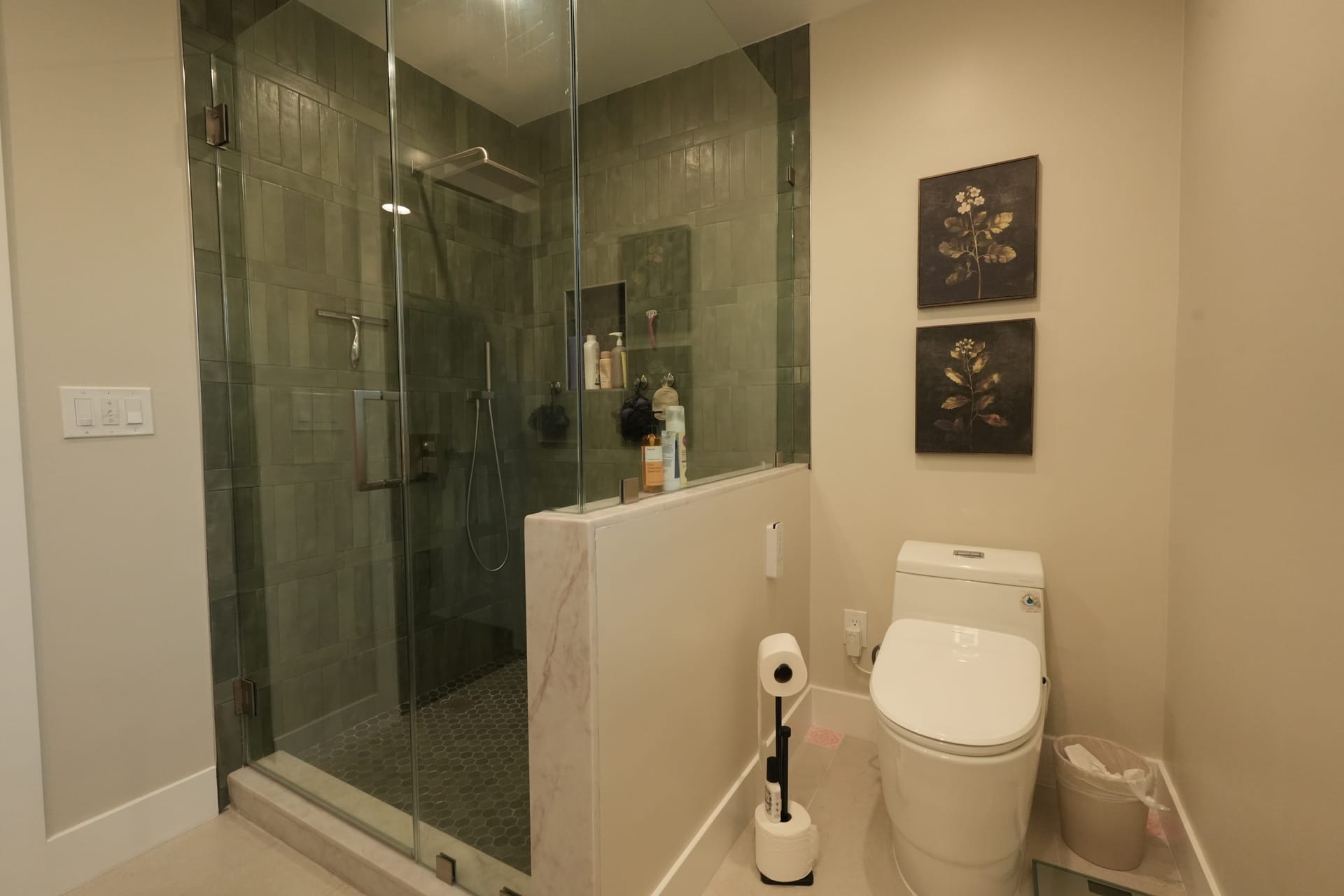 glass shower enclosure next to a toilet with framed wall art