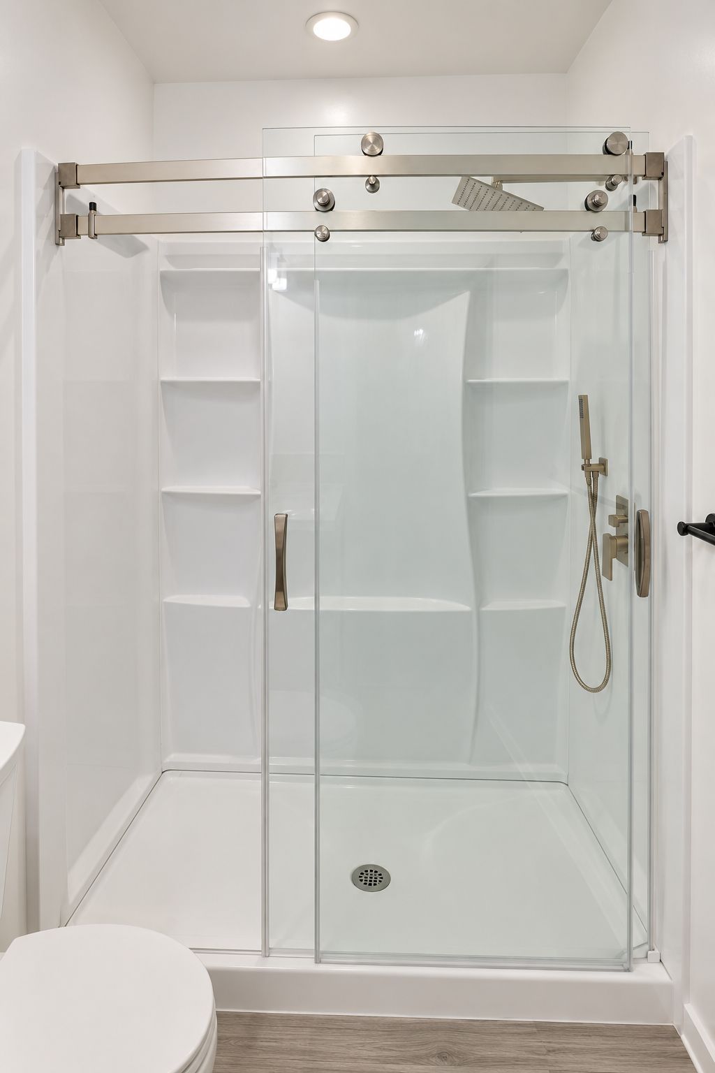 shower stall with sliding glass doors, tiled walls, and shower fixtures