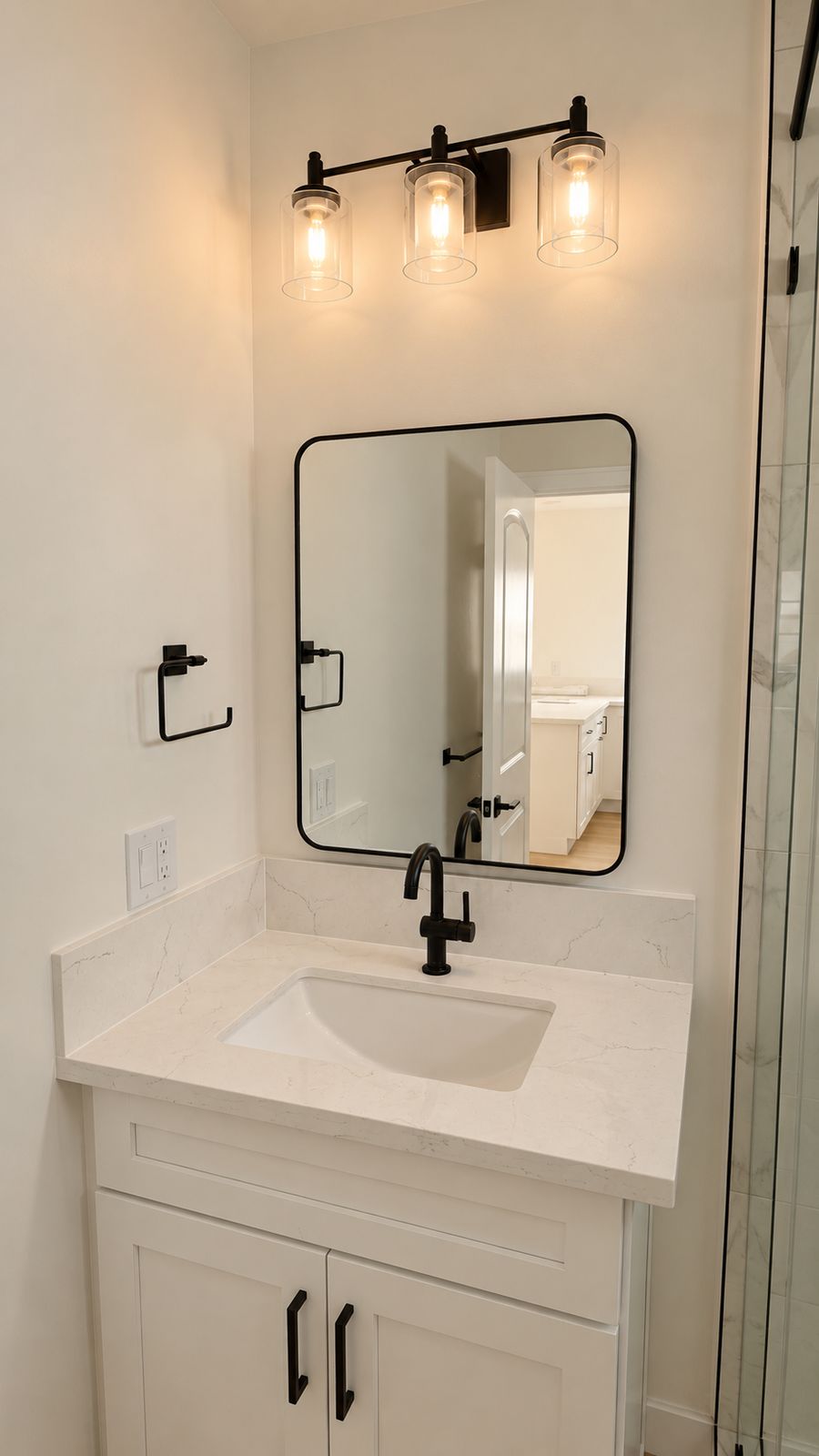 bathroom vanity with mirror, light fixture, and tiled shower visible