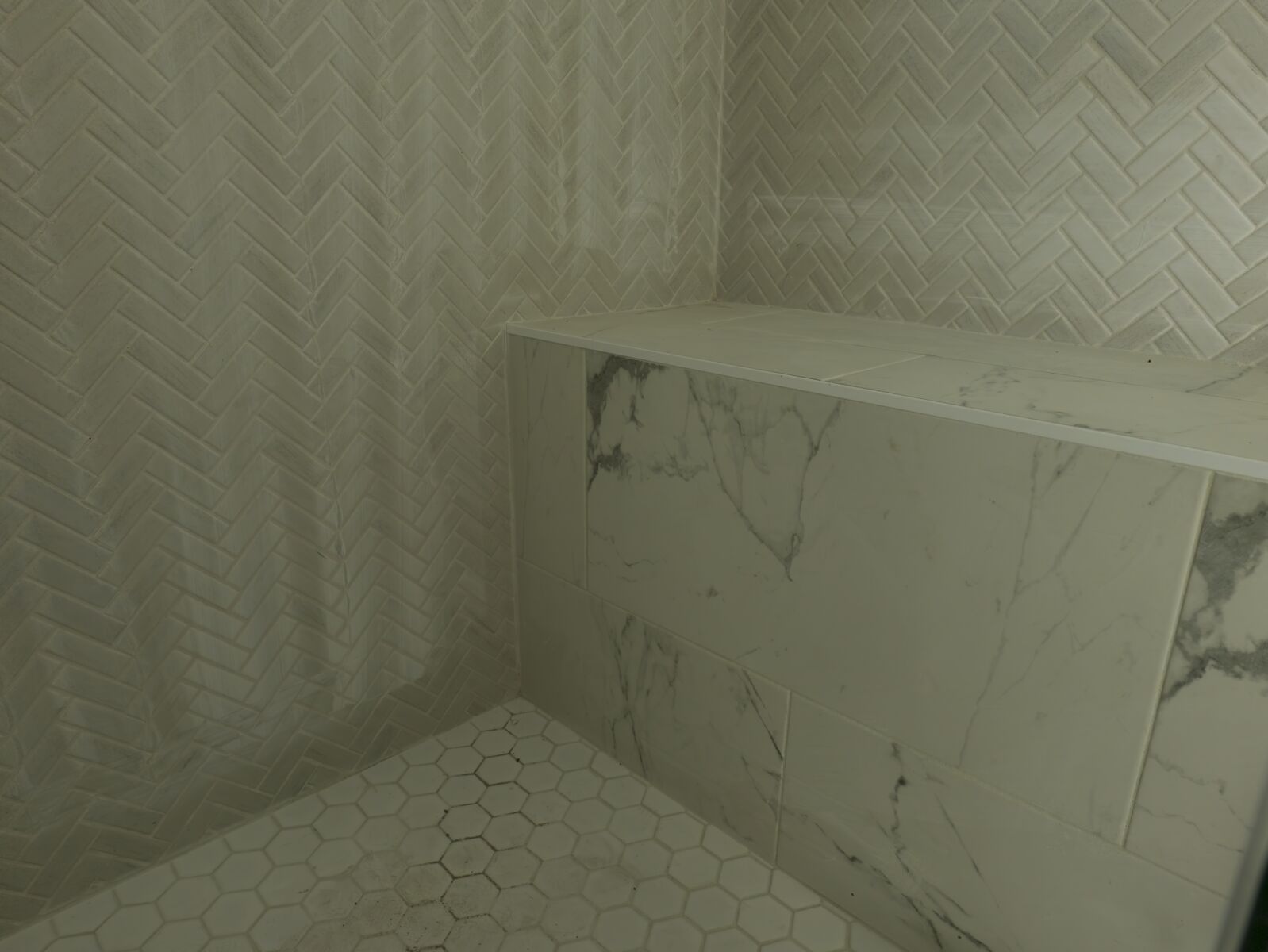 Shower floor with pale mosaic tile and dark fixtures