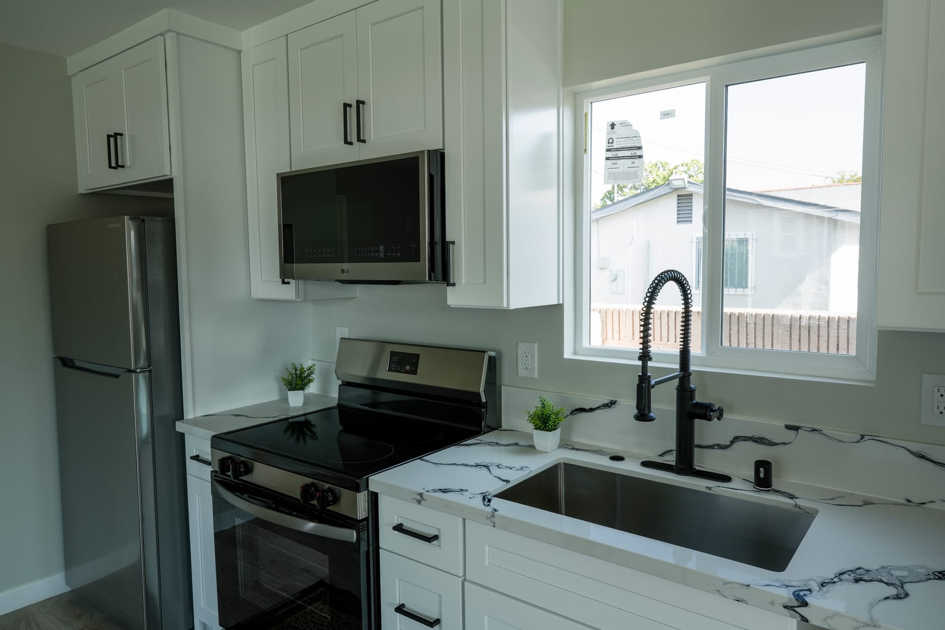 kitchen sink and peninsula with white shaker cabinets, black faucet, and window