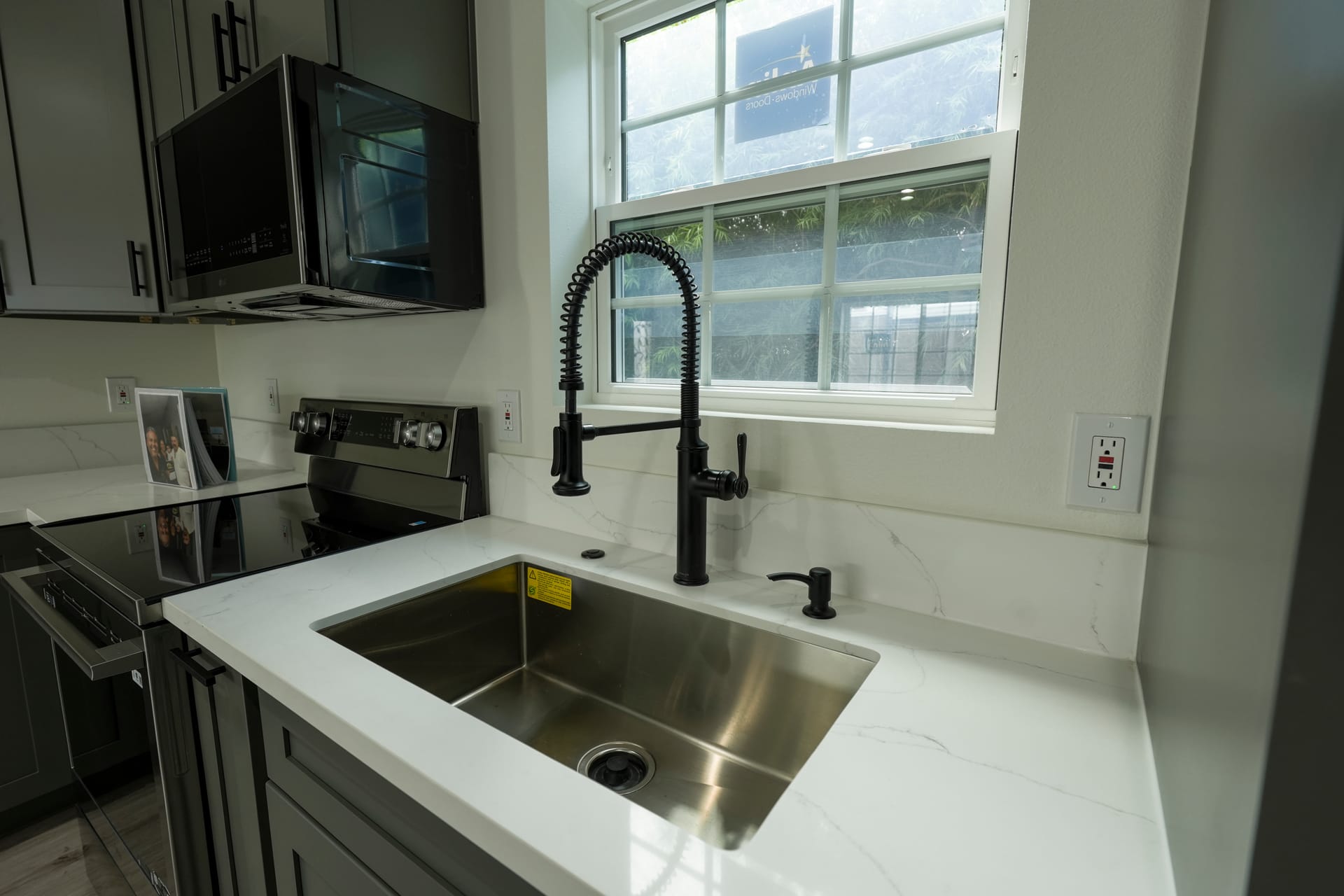 Kitchen sink and stone counter beneath a wide window