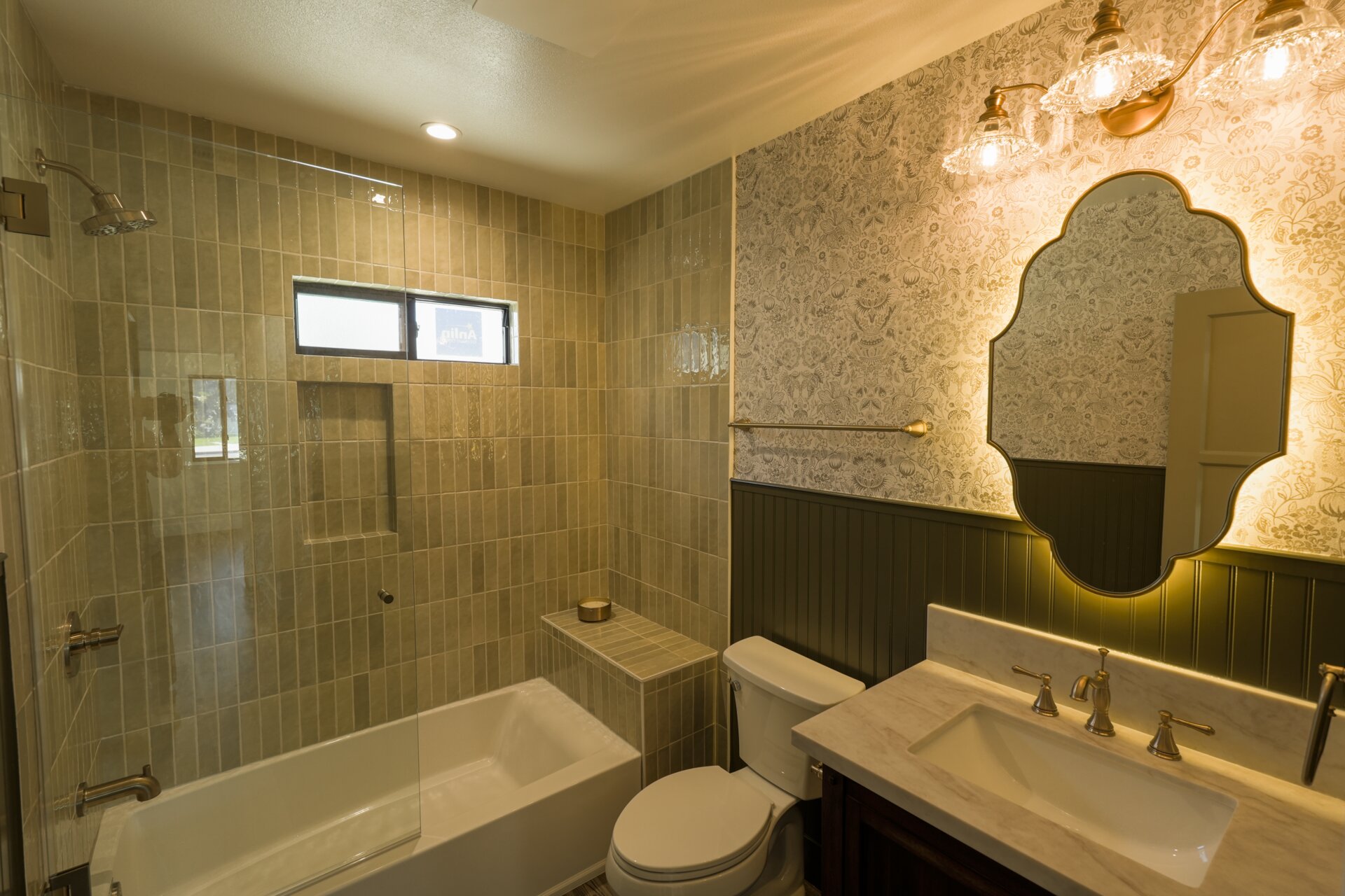 Warm stone bathroom with a glass shower and illuminated vanity mirrors