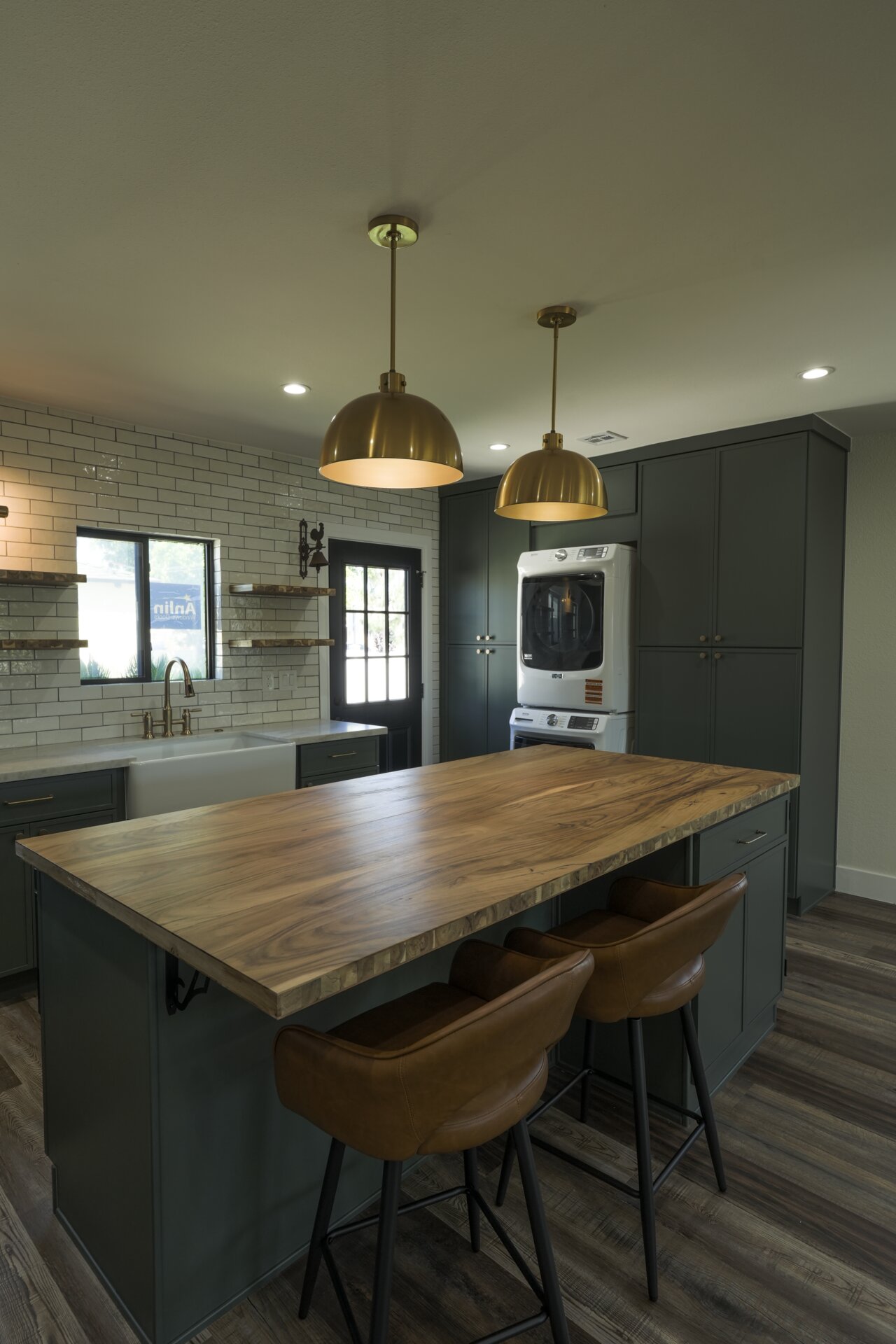 Open kitchen with a broad wood-topped island and deep green cabinetry