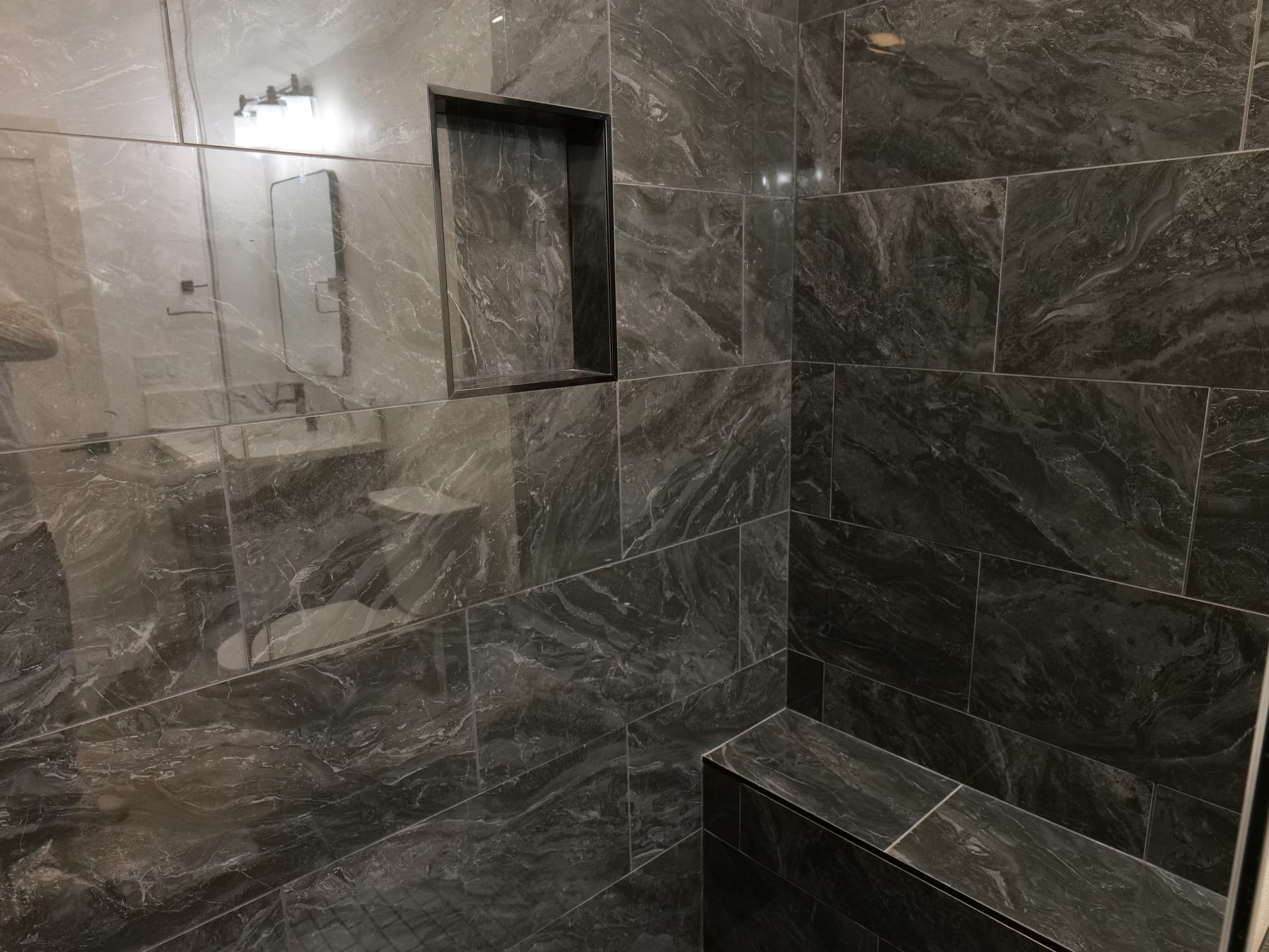 Stone shower tile with a recessed niche and built-in bench