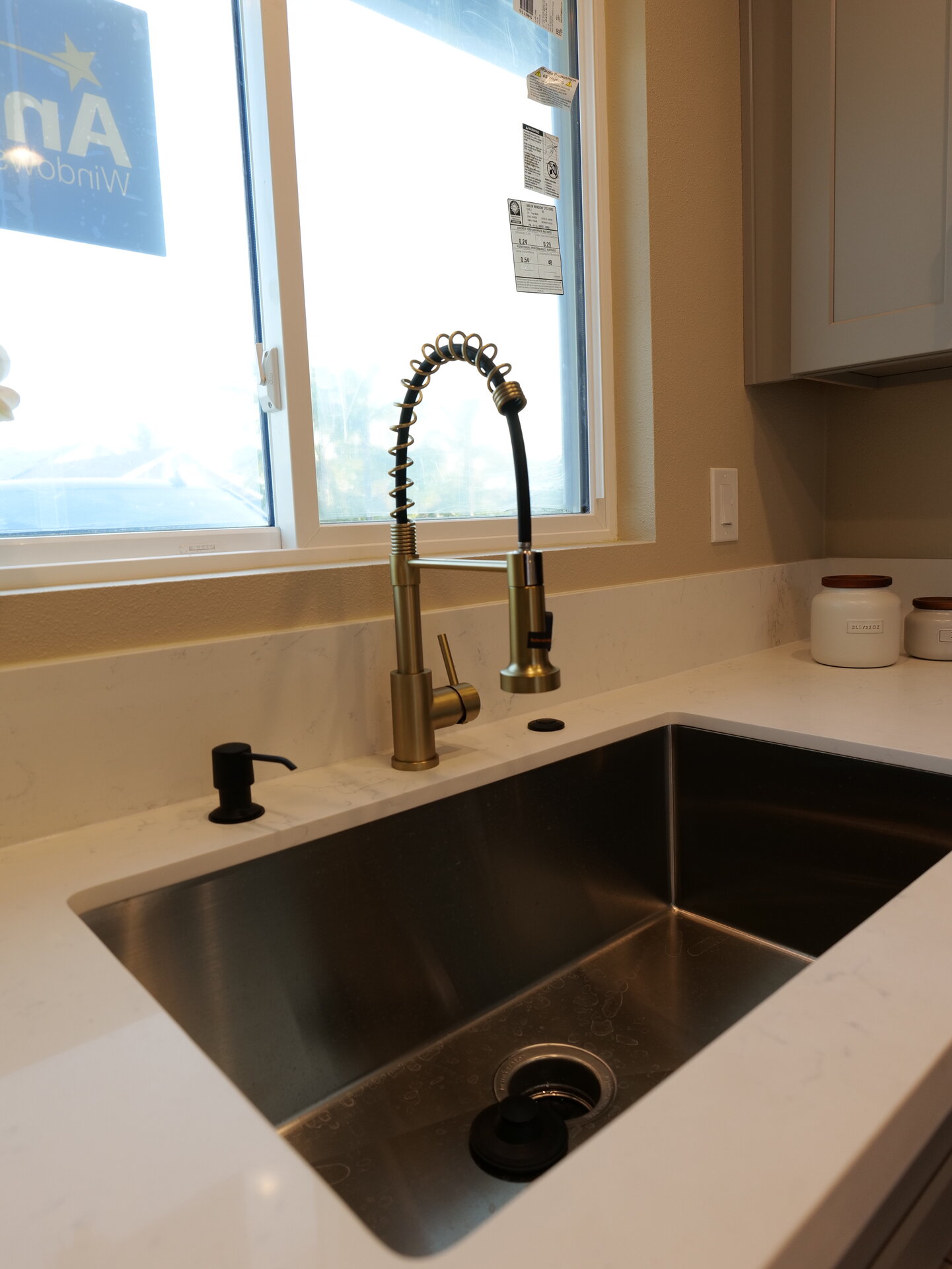 Kitchen sink beneath a bright window with a dark arched faucet
