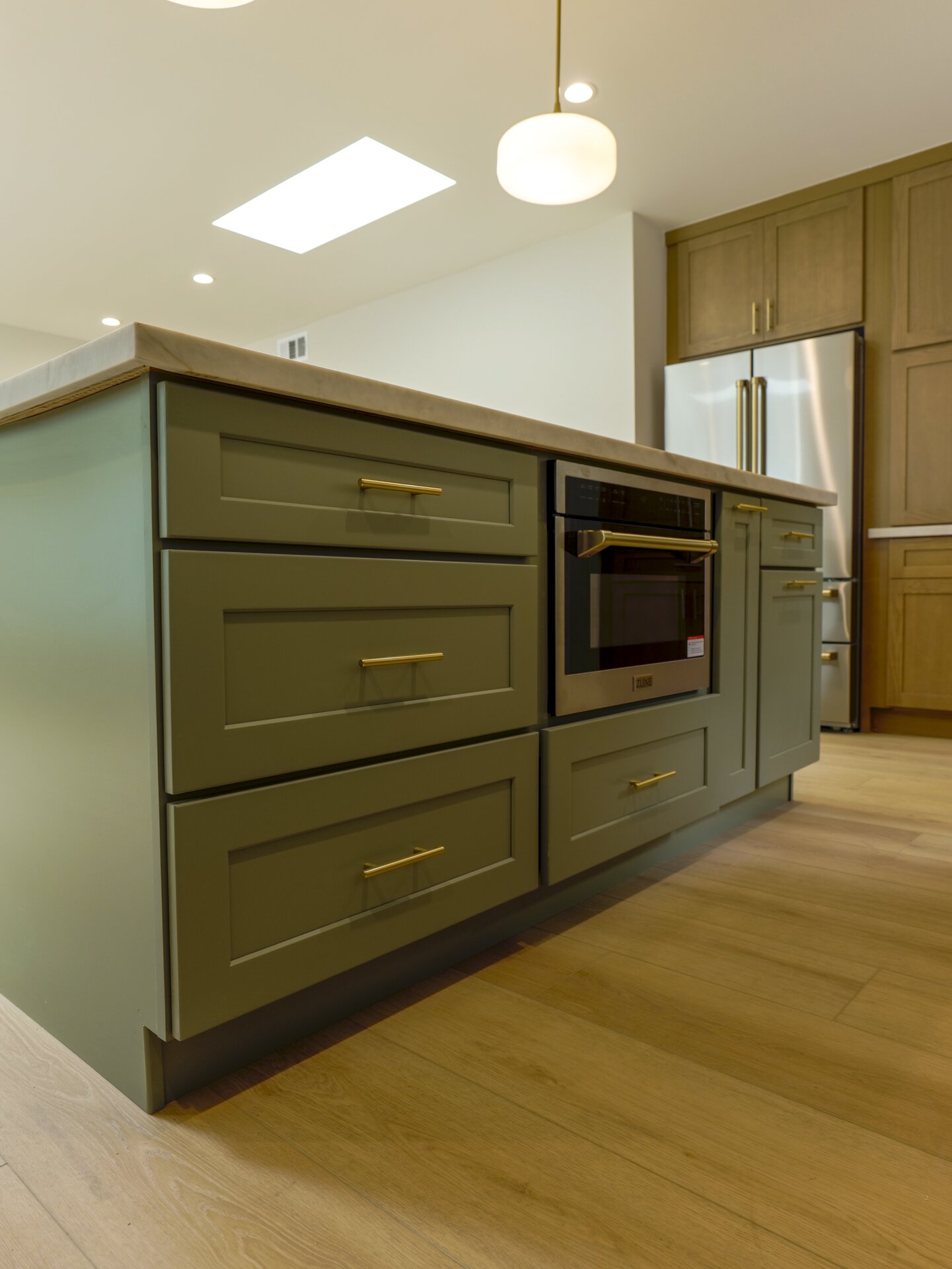 Green kitchen island with built-in appliances and wood countertop