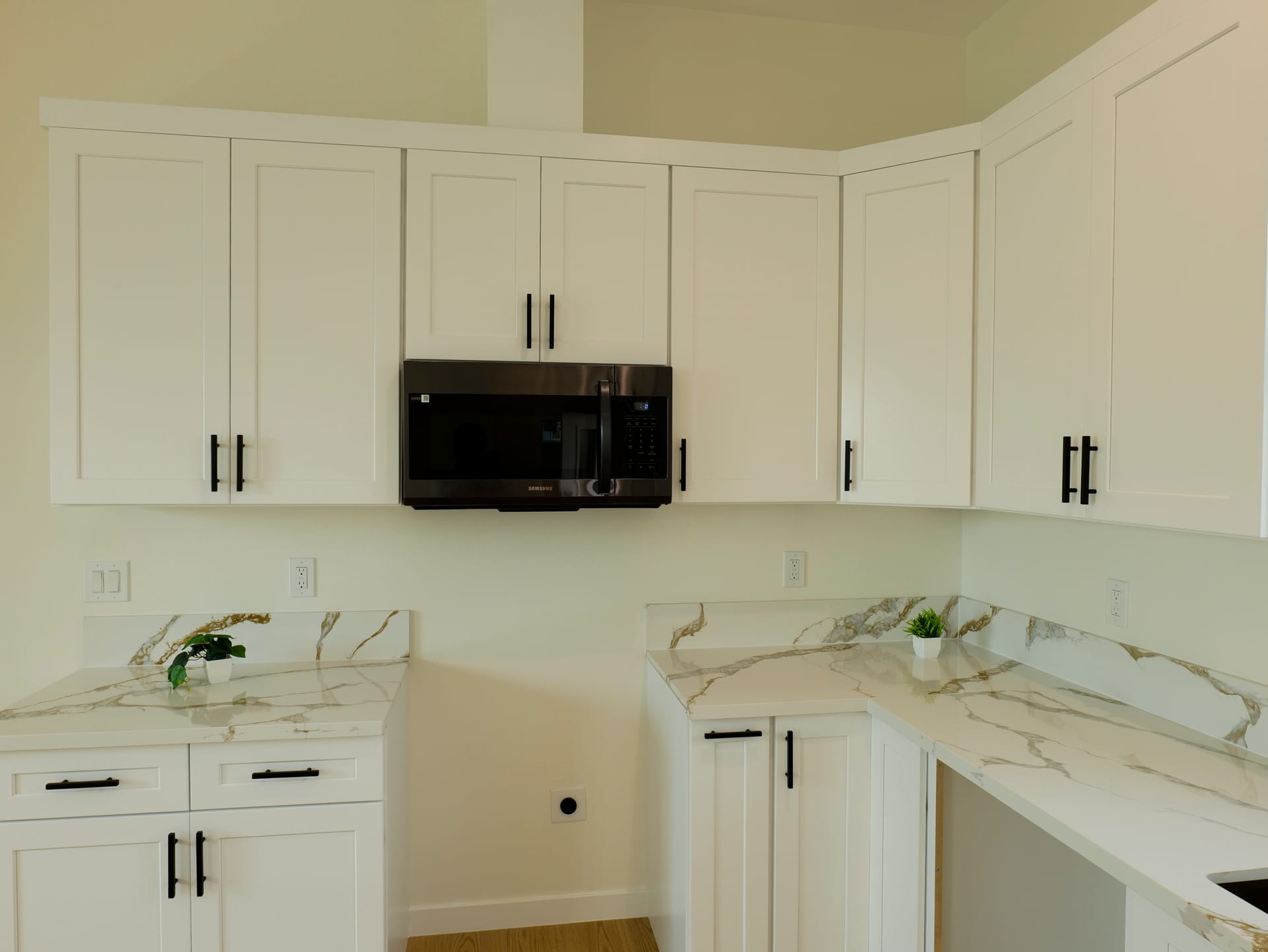 White kitchen with marble-pattern backsplash and contrasting dark fixtures