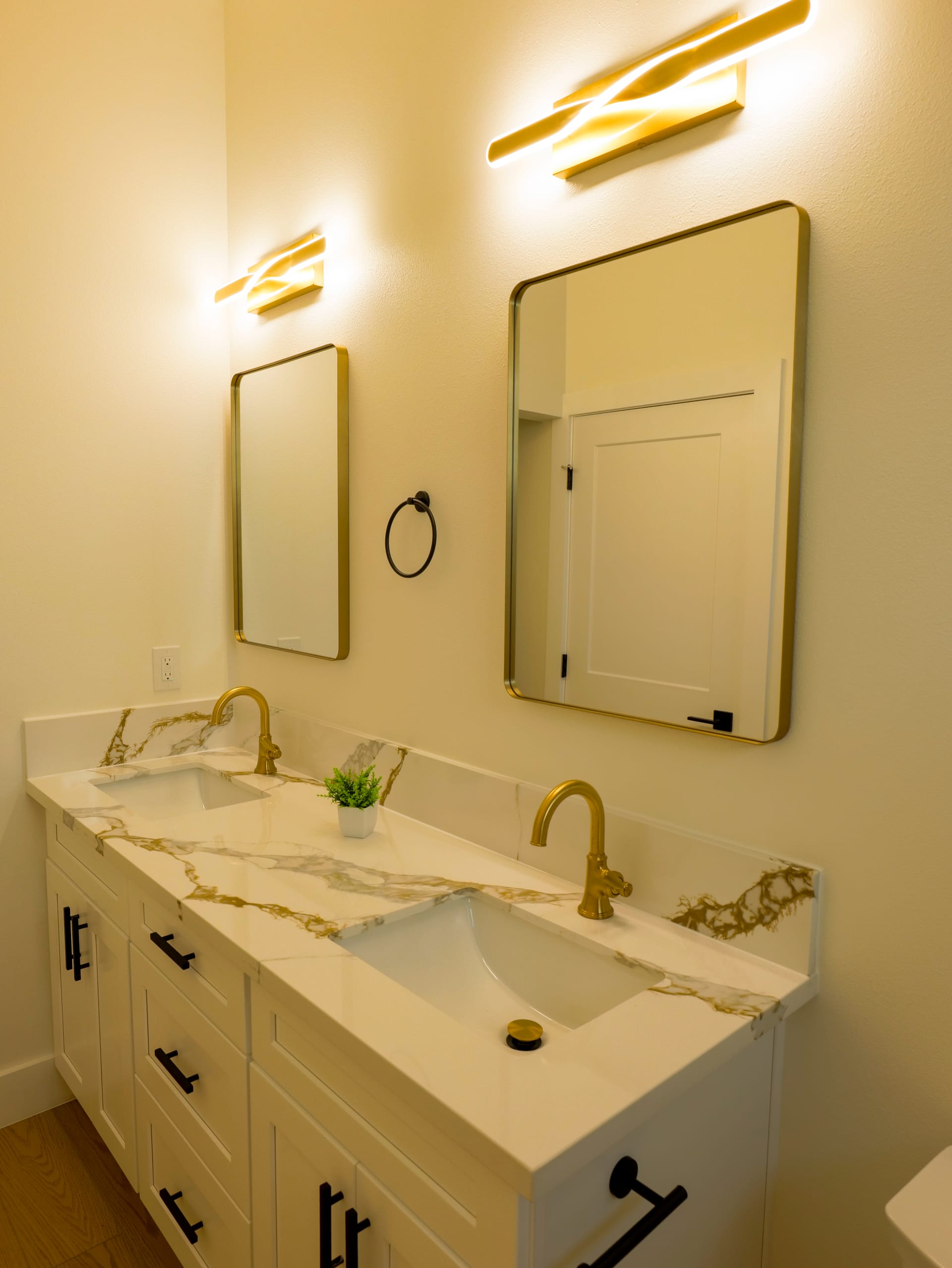 Double vanity with pale stone surfaces and warm metal fixtures
